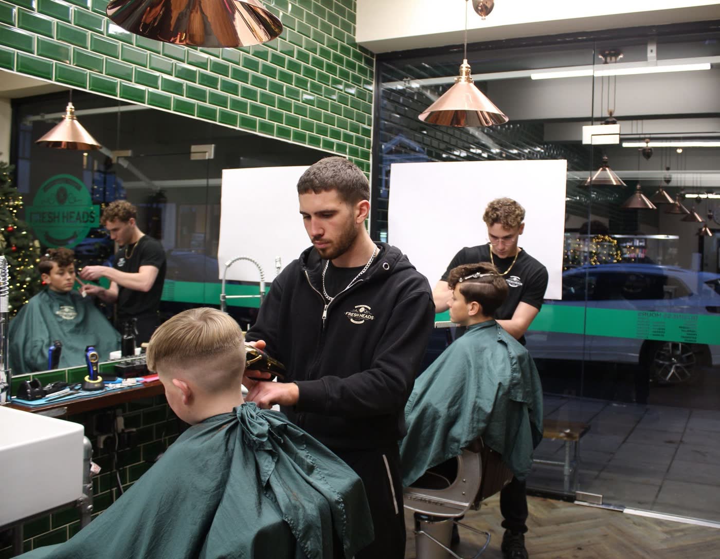 Two Fresh Heads barbers cutting boys' hair in the shop